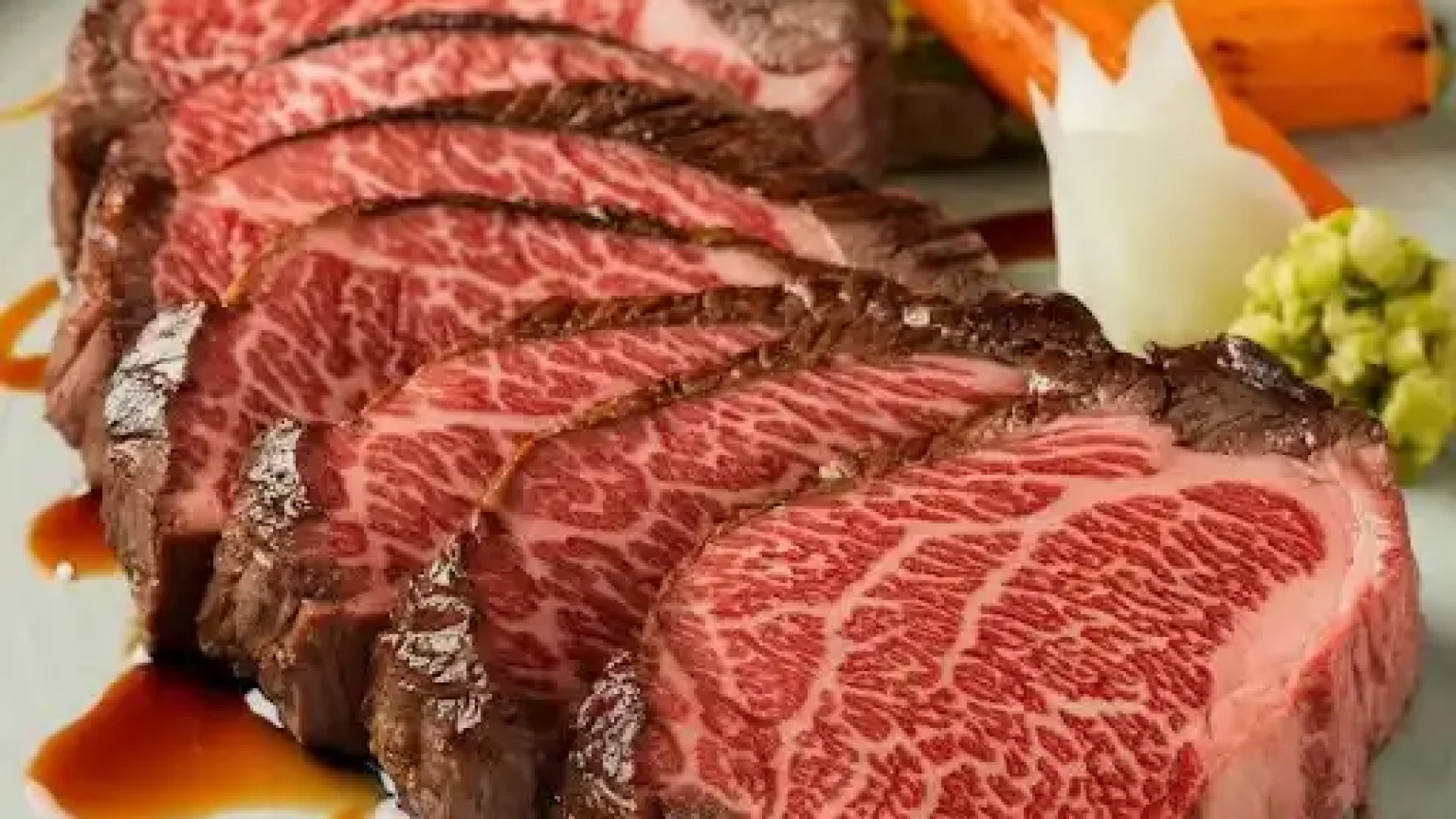 Slices of premium Wagyu beef steak, prepared rare to medium-rare, served with roasted vegetables and a side of wasabi.